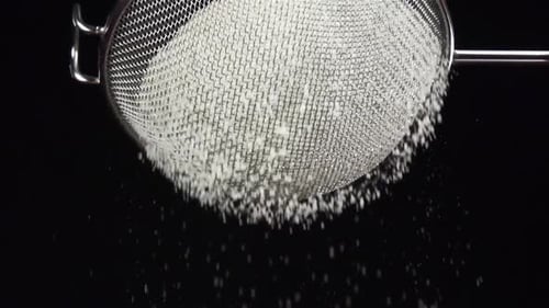 Flour Sift Through Sieve on Black Background in Slow Motion