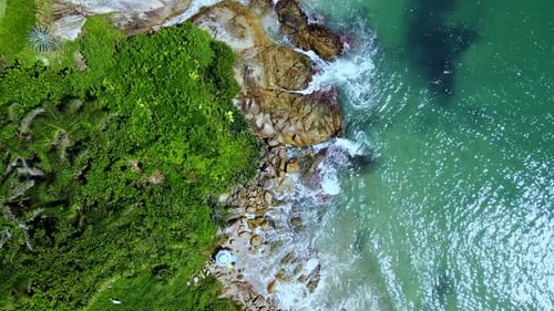Aerial Top View of Ocean Waves Reaching Beach Shore. Drone Footage moving slowly.