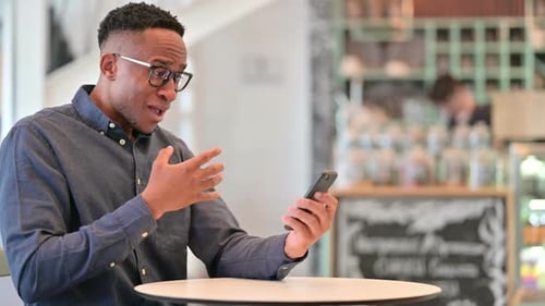 Man with Phone in Cafe Having Issue