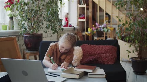 Ein kleines Mädchen sitzt im Wohnzimmer und schreibt in ein Notizbuch
