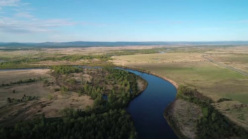 Aerial View of a River Flowing Through Rural Area with Meadows Rare Trees and with the Road on the