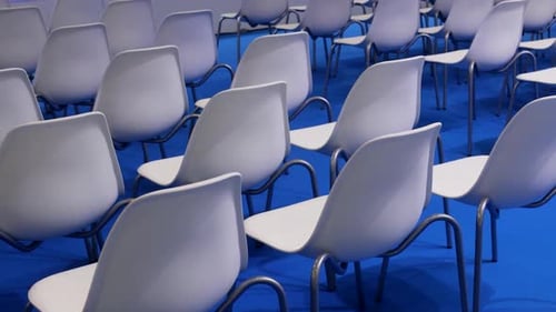 Empty White Chairs on a Blue Background in a Row