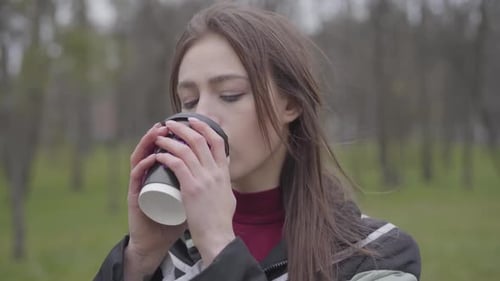 Close-up of Thoughtful Charming Girl Drinking Coffee Outdoors