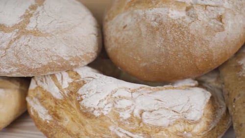 Frisches Vollkornbrot auf dem Holztisch. Verschiedenes Bäckereibrot. Dolly Schuss. Zeitlupe. Schliessen