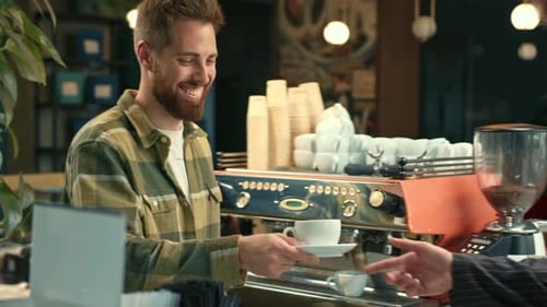 Handsome male barista gives coffee to a Man. Man buys coffee in a coffee shop.