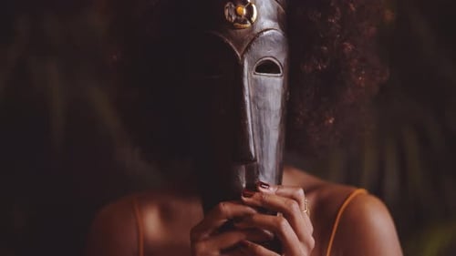 Woman With Afro Holding Traditional Mask Over Face