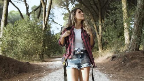 Trekkingmädchen geht auf Waldweg zum Campen