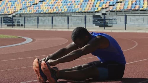 Hispanic Athlete Completing Set of Daily Exercises Sitting on Running Track