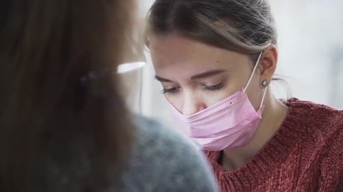 A young girl in a pink medical mask on her face does a manicure procedure. Close-up portrait.