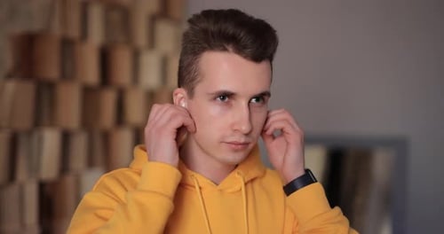 Young Adult Inserting Wireless Earbuds Indoors