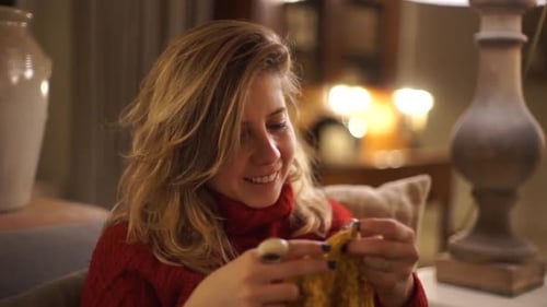 Woman Knitting Yellow Yarn on Couch Indoors