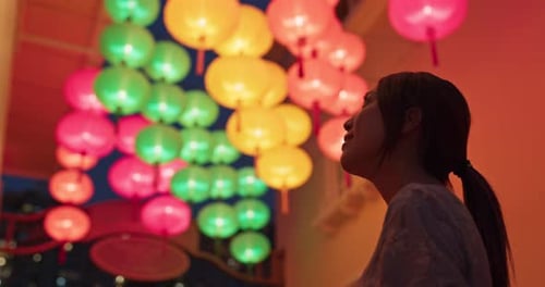 Woman Looks Up at Colorful Lanterns at Night