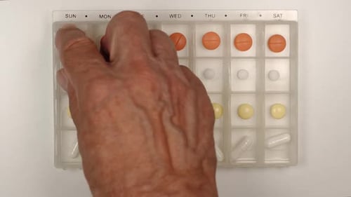Organized Medication: Hand Removing Pills From Organizer