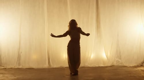 Silhouette of a Professional Dancer Performing in Studio in Soft Warm Lighting