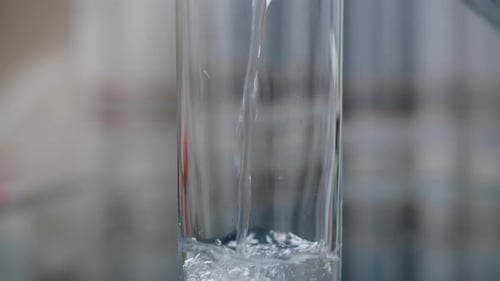 Pouring drinking water into glasses from a decanter, camera movement, close-up