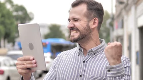 Man Celebrates Success Using Tablet in City