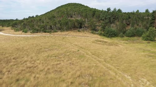 AERIAL: Flying Over Dry Meadow and Over Mountain to Horizon with Sea Visible in Background