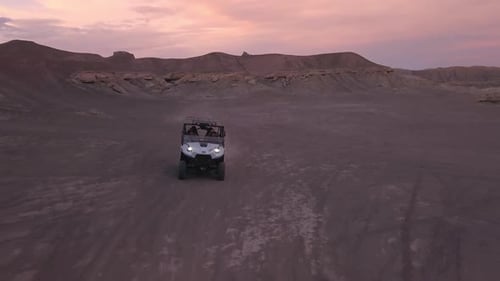 OHV driving over hill in the desert while flying backwards