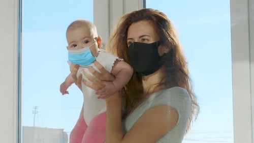 Woman Holding Baby with Surgical Mask Indoors