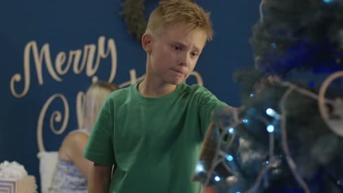 Boy Decorates Christmas Tree with Family in Home