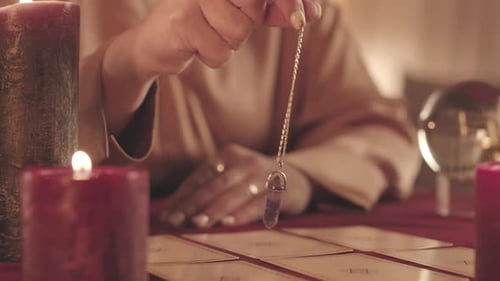Fortune Teller with Pendulum over Spread of Tarot Cards
