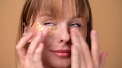 Close up Woman Applying Gold Eye Patches