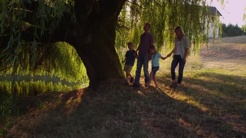 Family Walking Together Near Weeping Willow Tree
