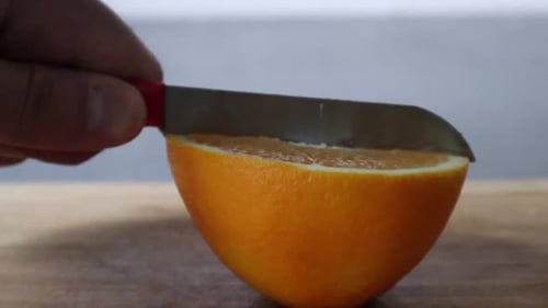 Time to slice an orange with a red knife. Slicing with yellow oranges.
Cut orange. Close up.