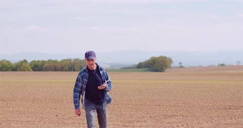 Farmer Examining Agricultural Field While Working on Digital Tablet Computer at Farm