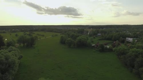 View of Forest, Lake and Country Houses Against Blue Sky with Sun and Clouds in Sunset at Summer