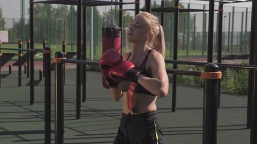 Blonde Woman Puts on Boxing Gloves Outdoors