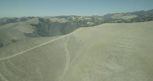 Helicopter aerial shot zooming into cityscape beyond green mountains, overcast day
