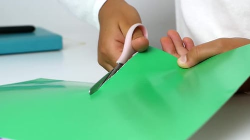 Close Up of Hands Cutting Green Paper