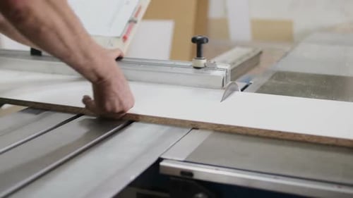 Carpenter Using Circular Saw for Cutting Wooden Board at the Workshop