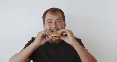 Man Enjoying Burger Against White Background