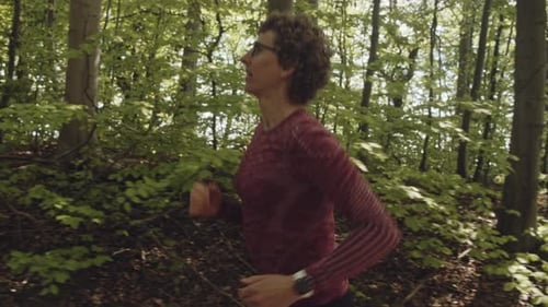 Determined Woman in Glasses Running Along the Forest Path Early Morning