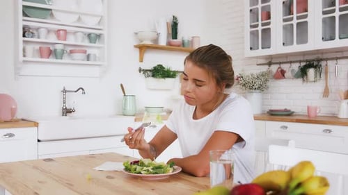 Tätowiertes Model sitzt am Tisch und fühlt sich traurig und unzufrieden mit der Diät, die keinen Salat essen möchte