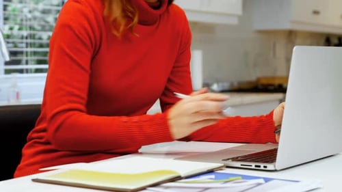 Woman Working on Laptop and Taking Notes at Home