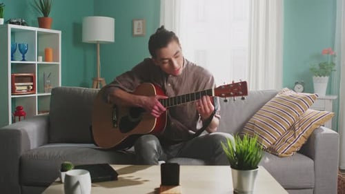Young Adult Playing Guitar in Living Room