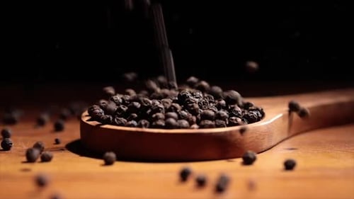 Black Tellicherry Peppercorns in Wooden Spoon on a Kitchen Table
