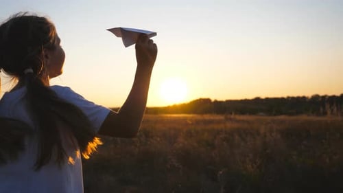 Follow to Happy Small Girl Running with a Paper Airplane Through Grass Field
