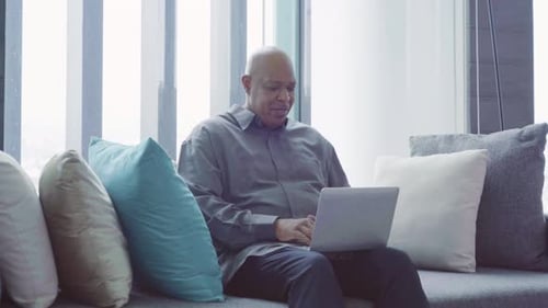Man Working on Laptop Computer on Sofa at Home