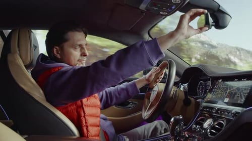 The driver adjusts the rear view mirror while driving the car