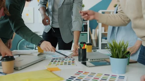 Hände kreativer Designer, die während eines Meetings im Büro mit Farbpaletten arbeiten