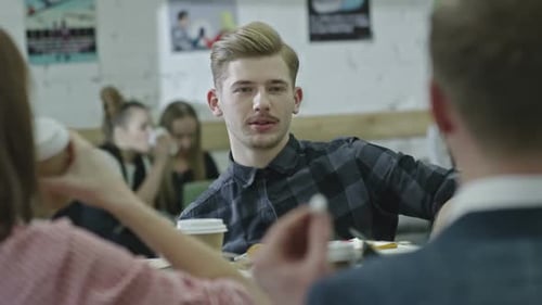 Jeune professionnel utilisant un gadget et discutant avec des collègues