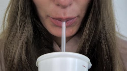 Woman Sips Drink With Straw Close Up