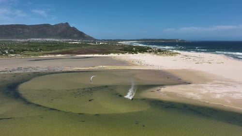 Drohnen-Tracking-Kitesurfer im flachen Strandteich drehen sich in hoher Luft auf den Kopf