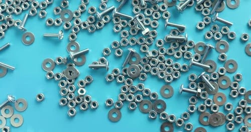 Draufsicht auf Metallschrauben und Muttern auf blauem Hintergrund
