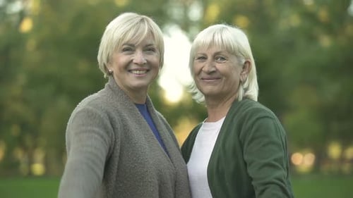 Smiling Senior Women Showing Thumbs Up Gesture, Hugging and Resting at Park
