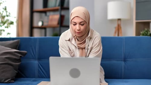 Woman Working on Laptop on Sofa at Home